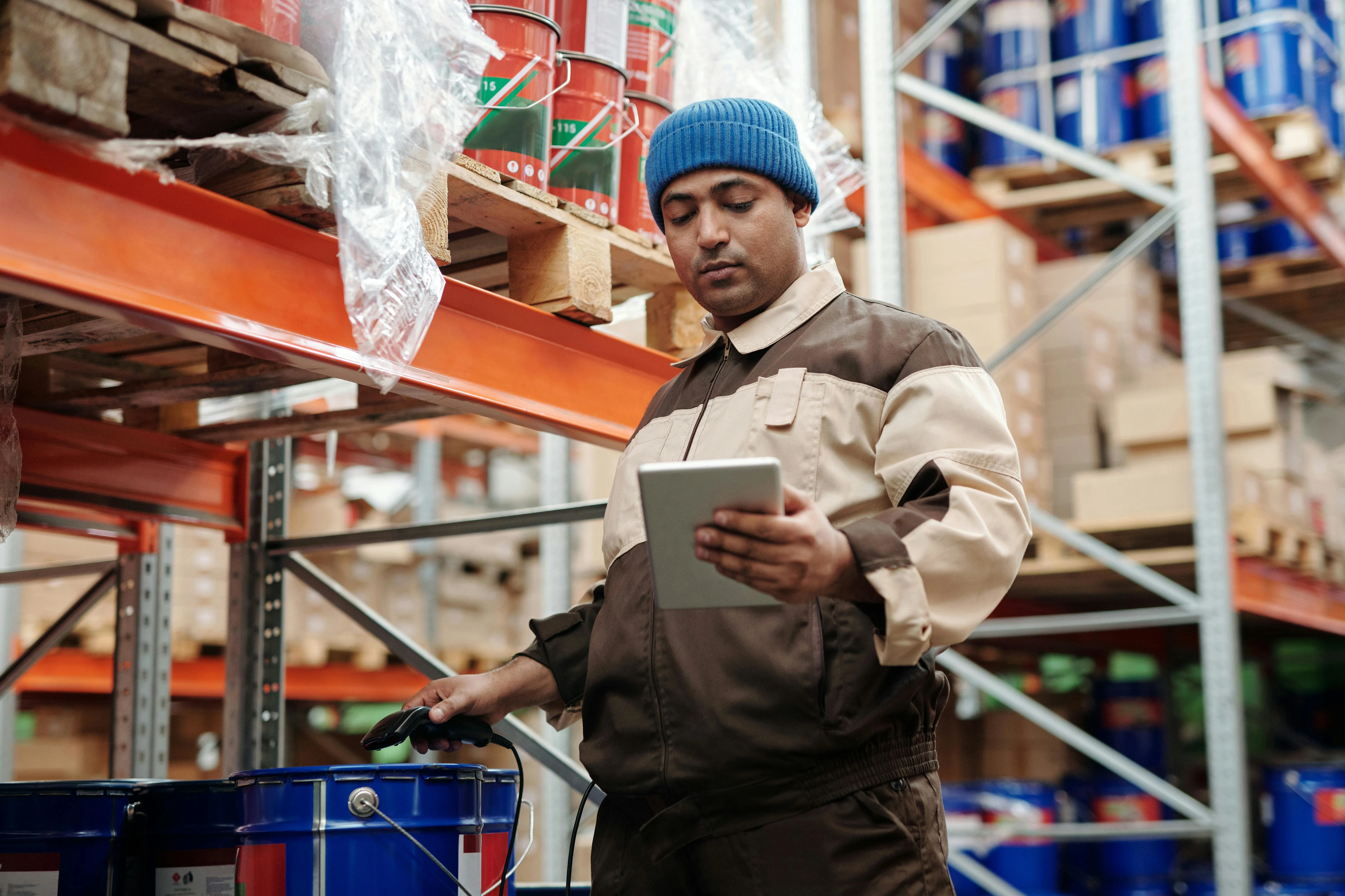 A warehouse worker checking stock on a tablet while holding a barcode scanner