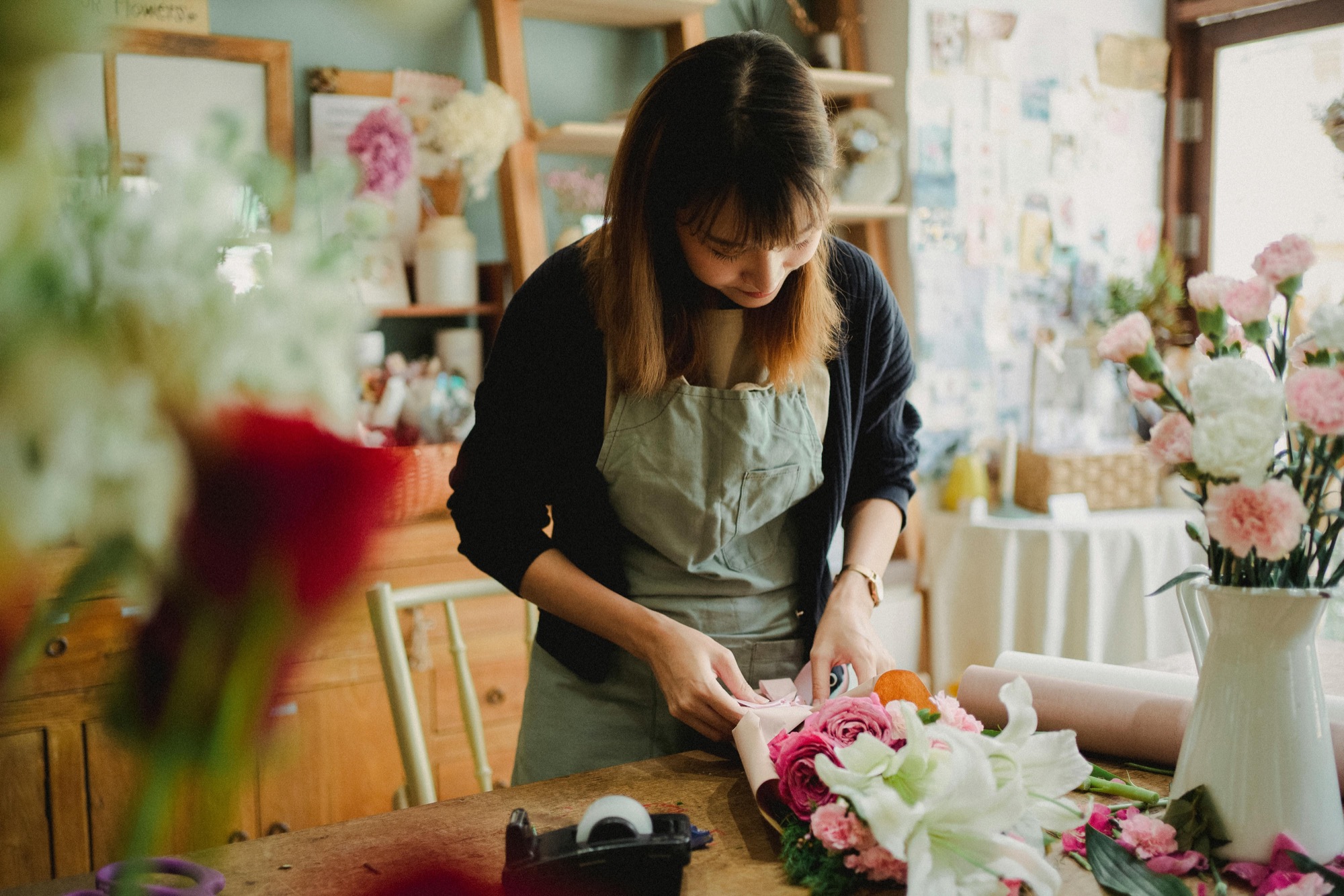 A florist wrapping a bouquet at a workbench
