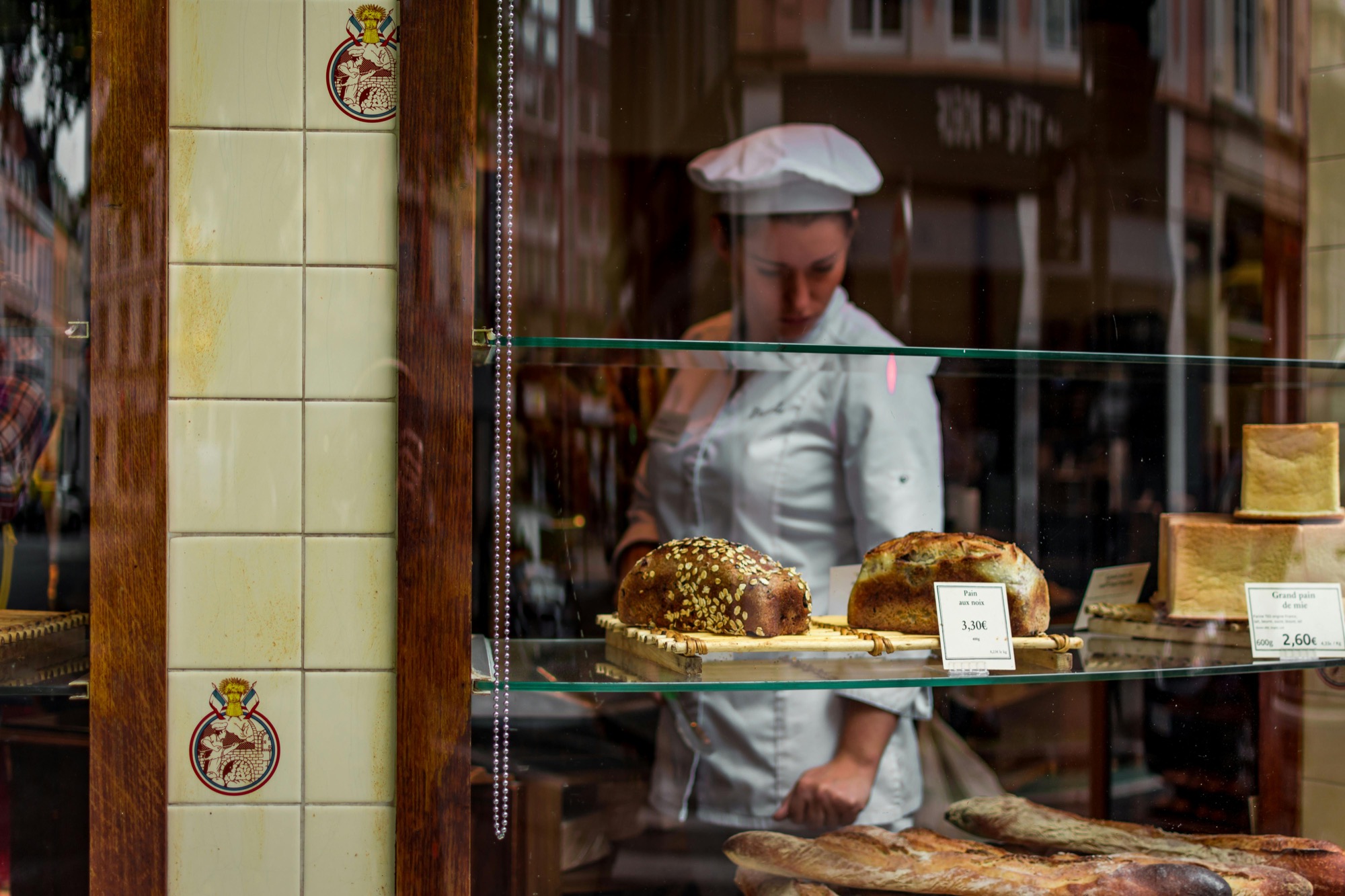A baker behind a glass counter of fresh bread