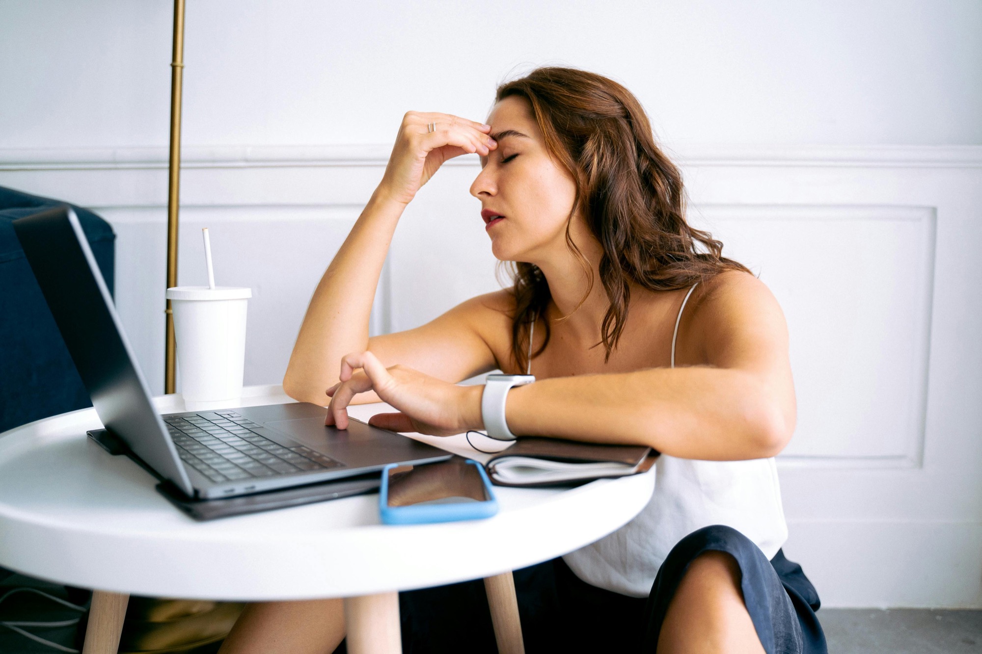 A stressed person at a laptop with a hand on their forehead